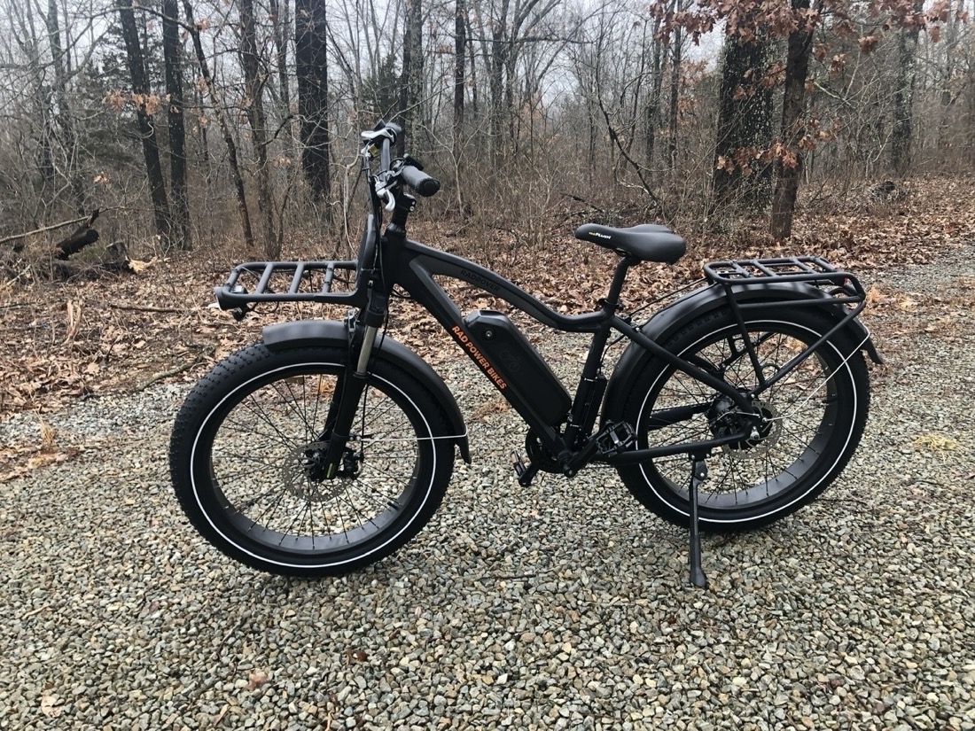 A black fat tire electric bike on a gravel road in the winter woods