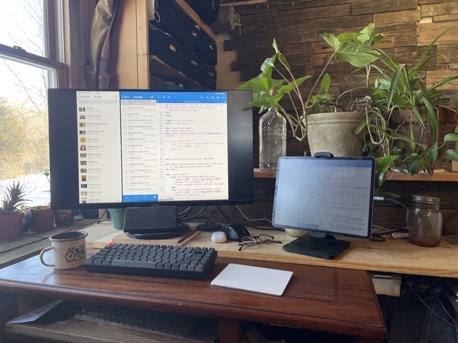 An iPad Pro in a stand is attached to an external display. In front of the dispaly is a keyboard and trackpad.