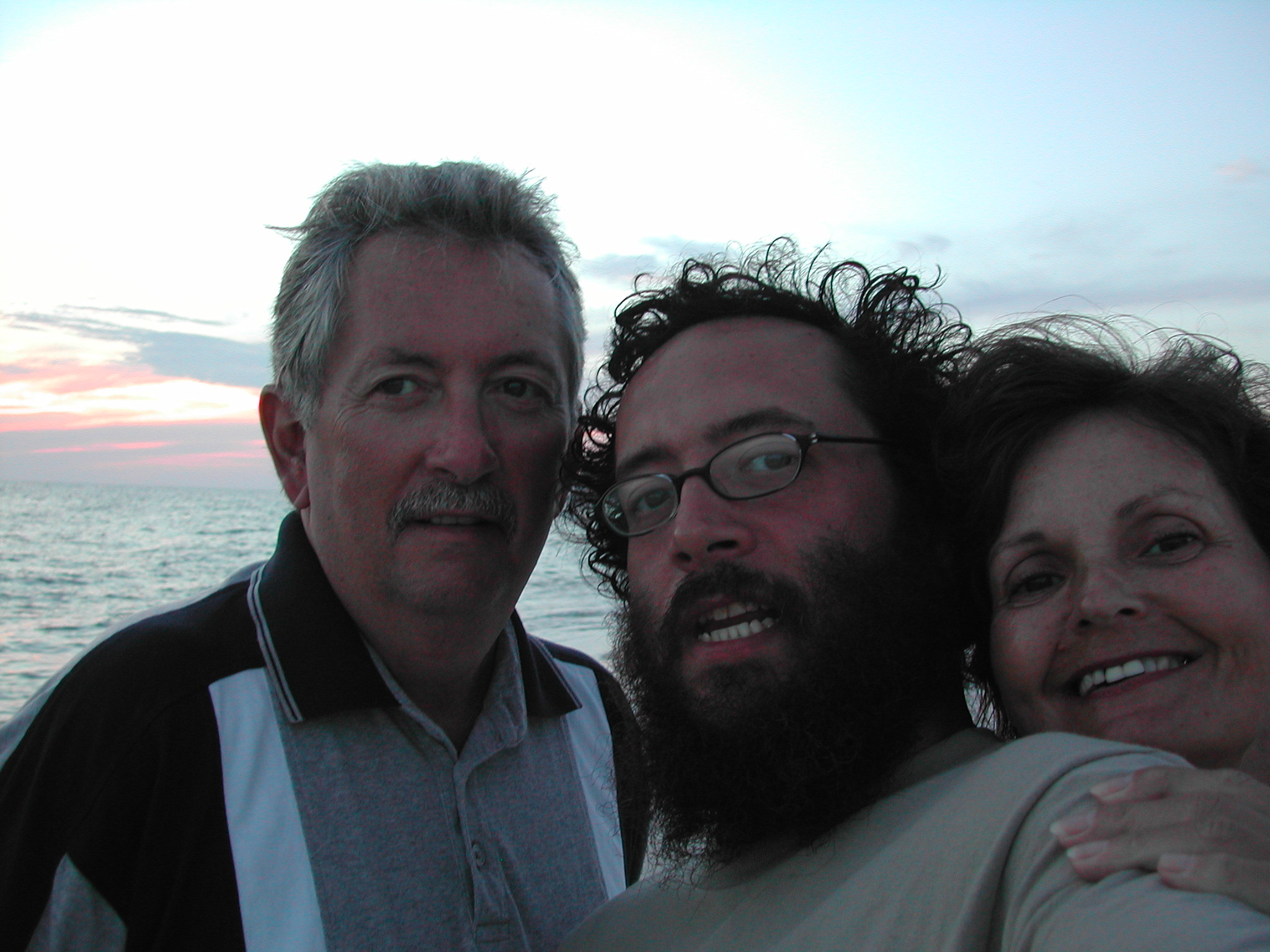 3 people, two men and woman taking selfie at the beach at sunset