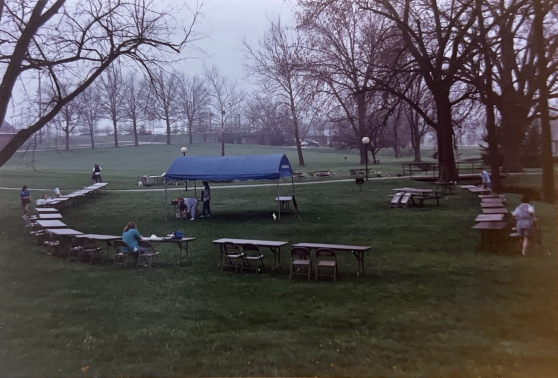 Empty tables arranged in a semi-circle on a grass lawn