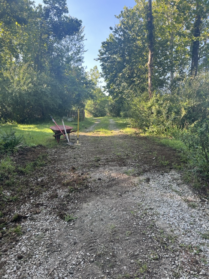 A gravel road being covered in dirt