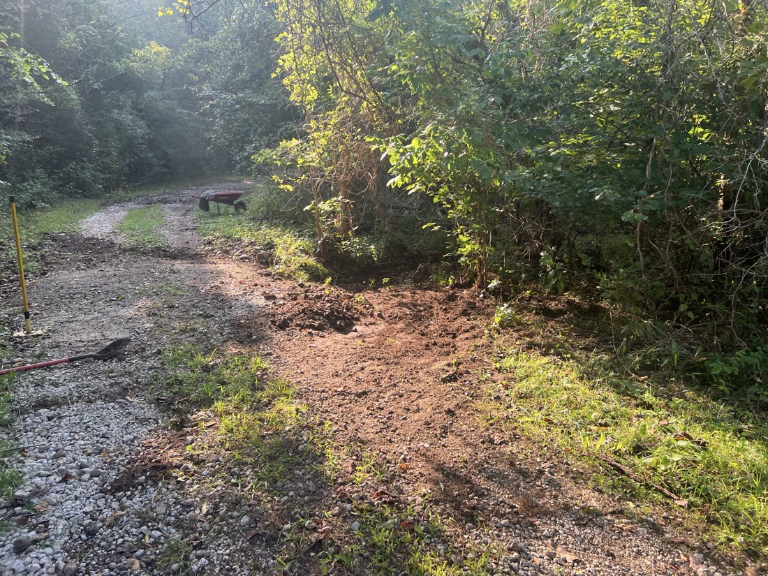 A photo of an area near a creek and road with fresh dirt where debris was removed