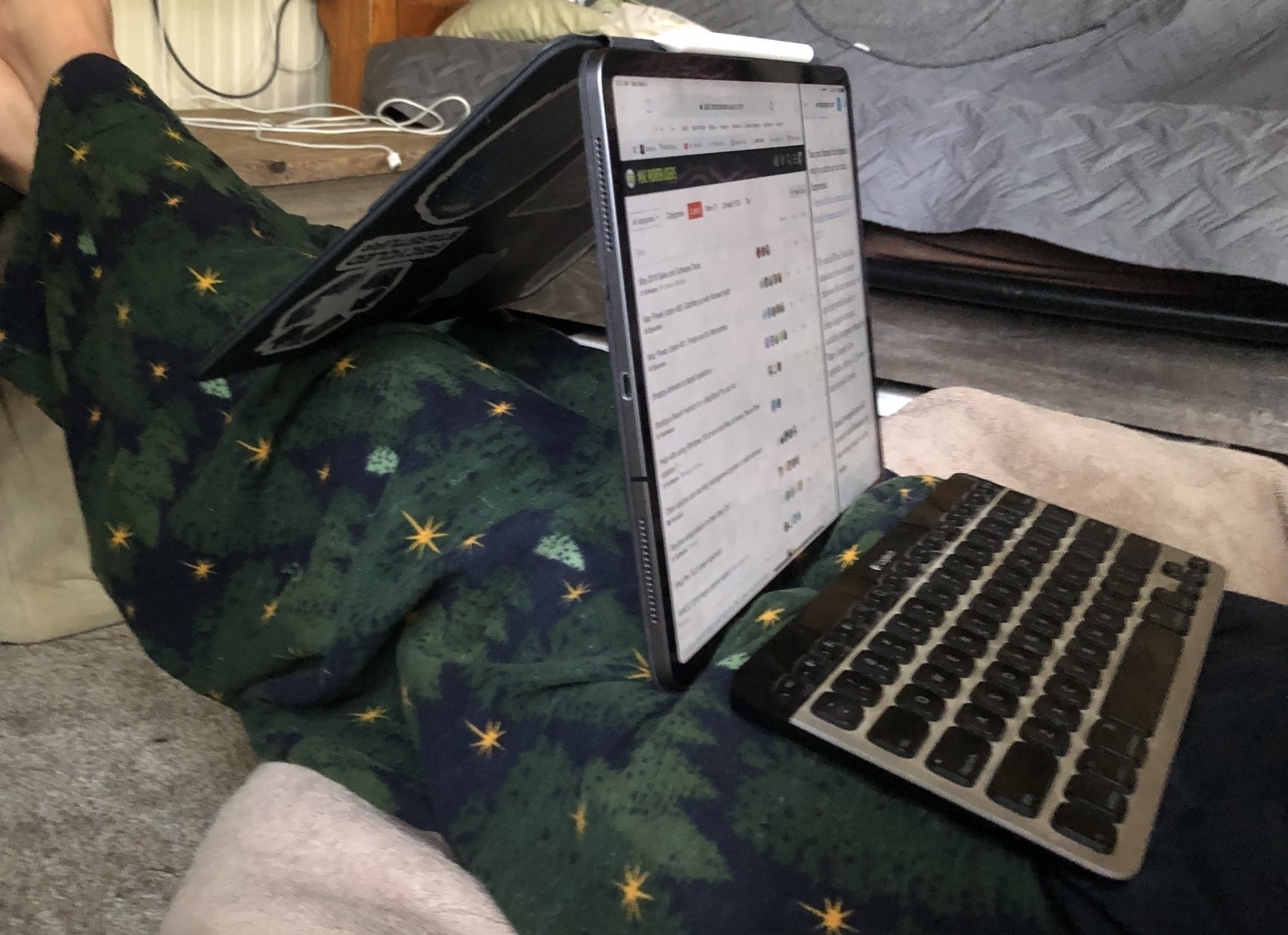 An iPad Pro in a Smart Keyboard Folio is in a backwards A-Frame and resting on outstretched legs that are propped up on a table. A keyboard sits in front of the iPad Pro