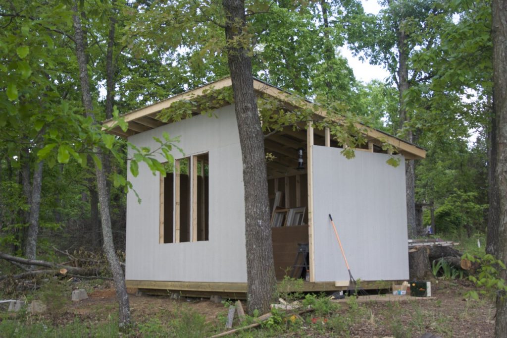 The nearly complete shell of my cabin. It now has walls but no door. The walls are an unpainted gray color.