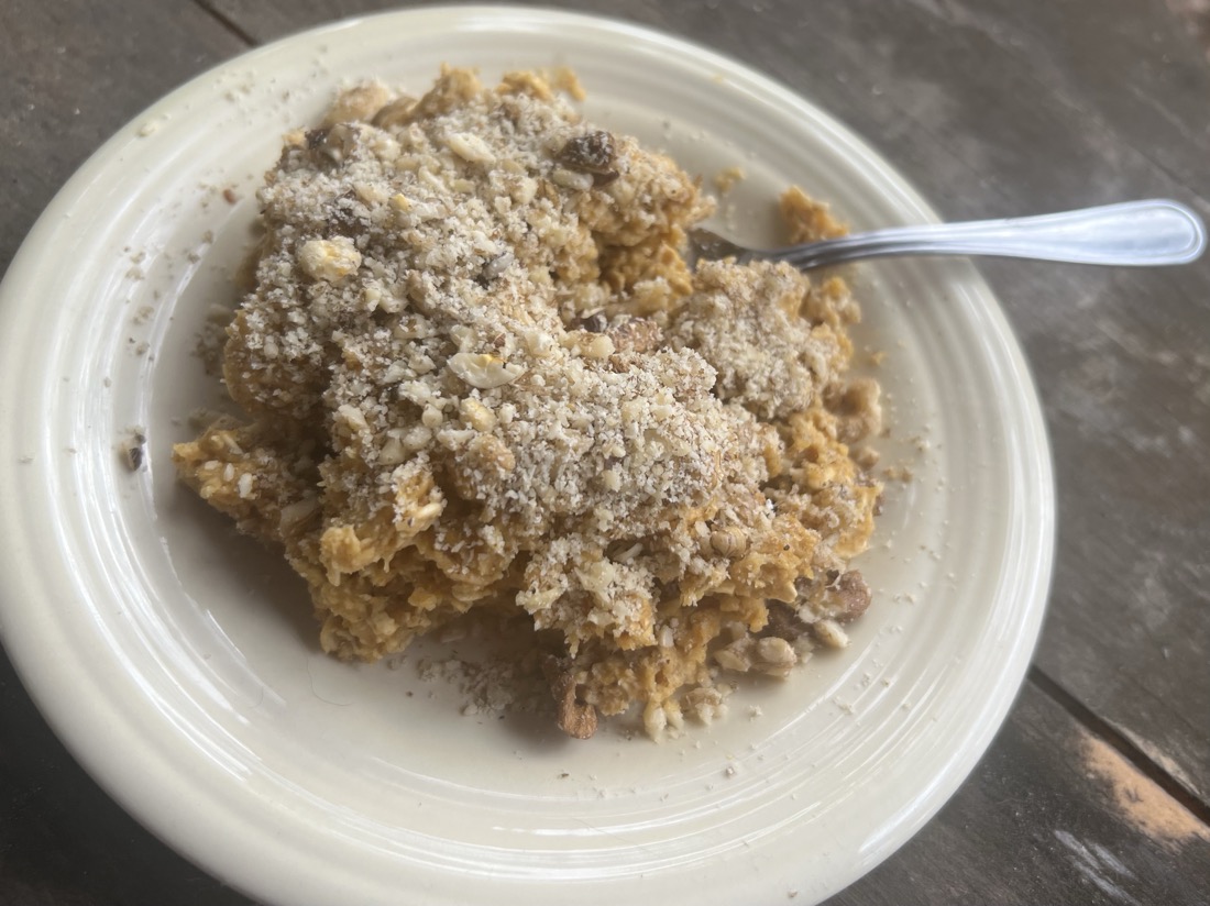 An image of baked pumpkin oatmeal topped with chopped walnuts served on a yellow plate