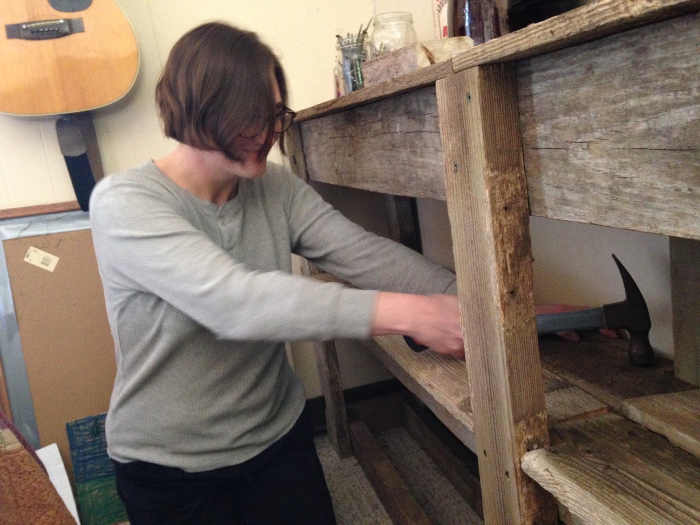 A woman with glasses and short brown hair is building old rustic wood shelves