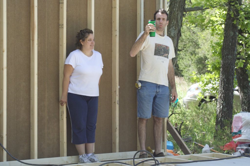 My sister and brother-in-law standing on the new floor. Behind them is the first wall which is framed and has siding attached