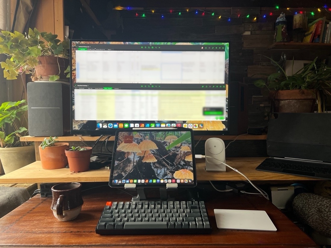 A photo of an iPad Pro on a desk. The iPad is attached to an external screen and keyboard. Two spreadsheet documents are open on the external display.