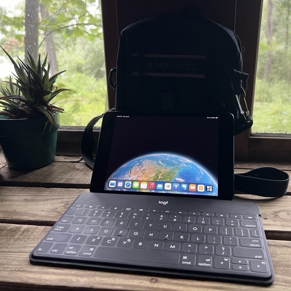 An iPad mini leans against a small pack. In front of the iPad is a very thin, black keyboard